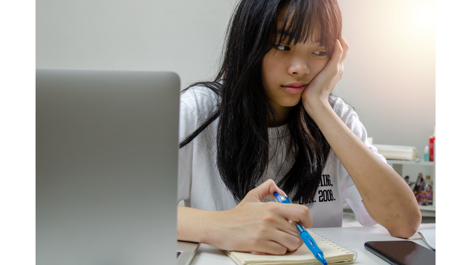 jeune-fille-pensive-tenant-un-stylo-devant-un-cahier-et-un-ordinateur-portable